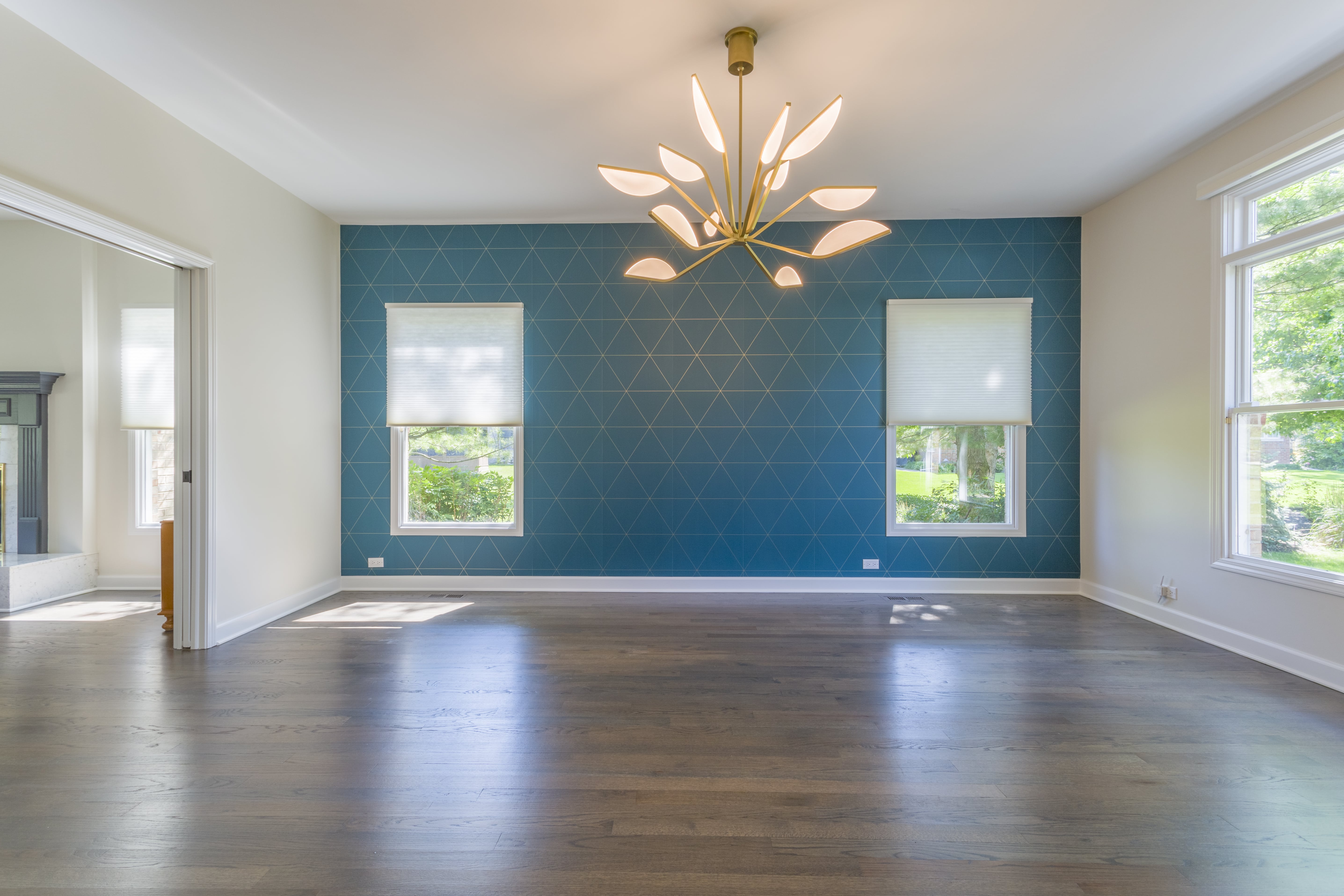 Living space with teal wall with gold geometric pattern and gold flower chandelier 