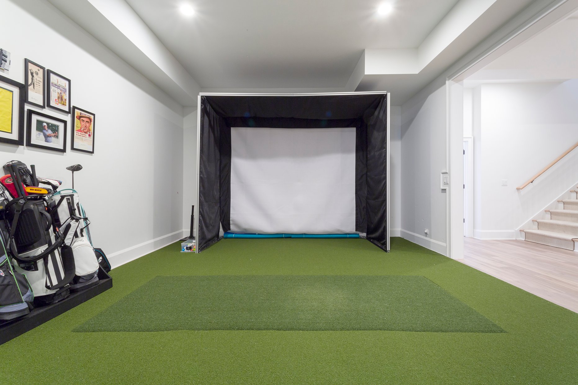 Golf Simulator in a finished basement with faux grass flooring 