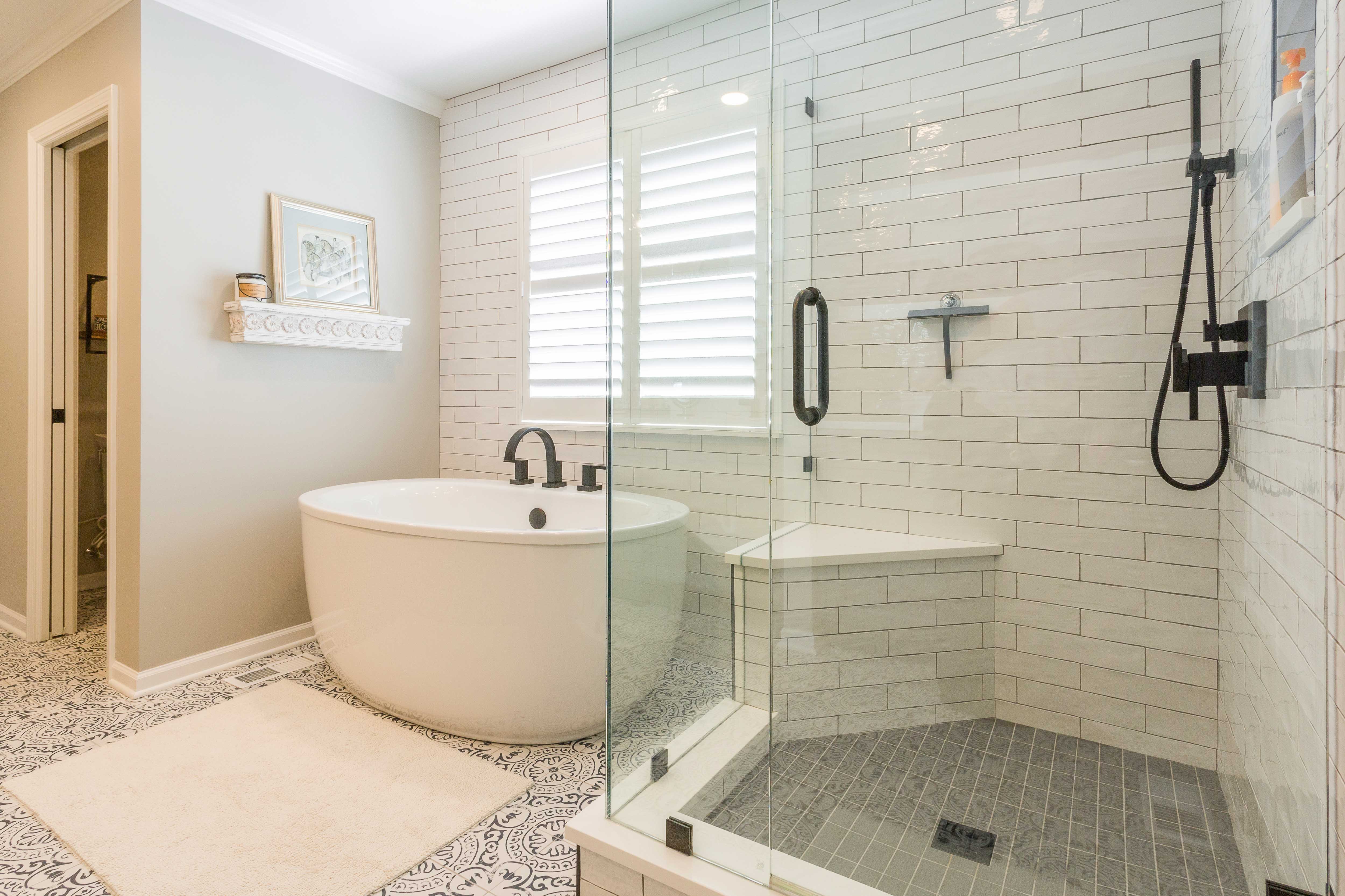 bathroom with beige walls white subway tile backsplash large stand alone tub walk-in shower with bench 