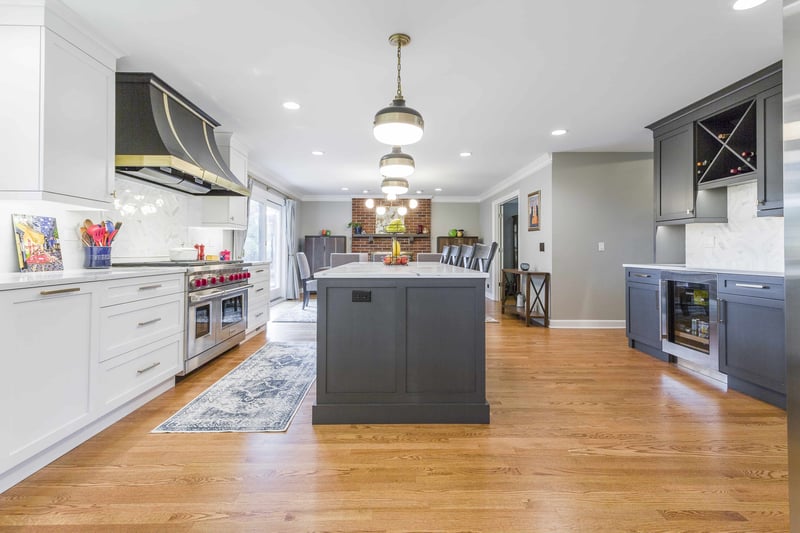 Black & White kitchen with an island, beverage center, and custom range hood. 