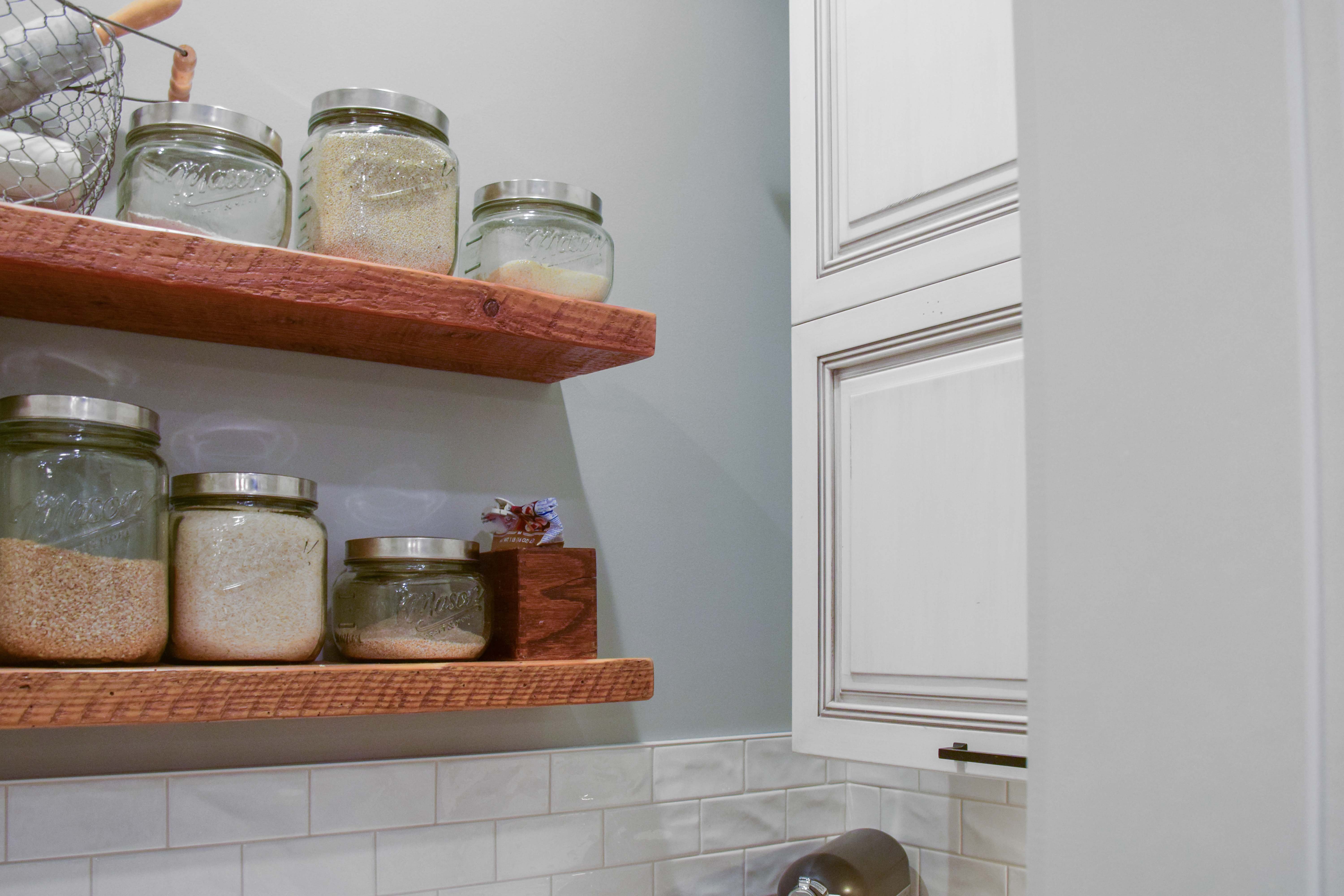 Walk-in pantry with wood shelves and glass jars. 
