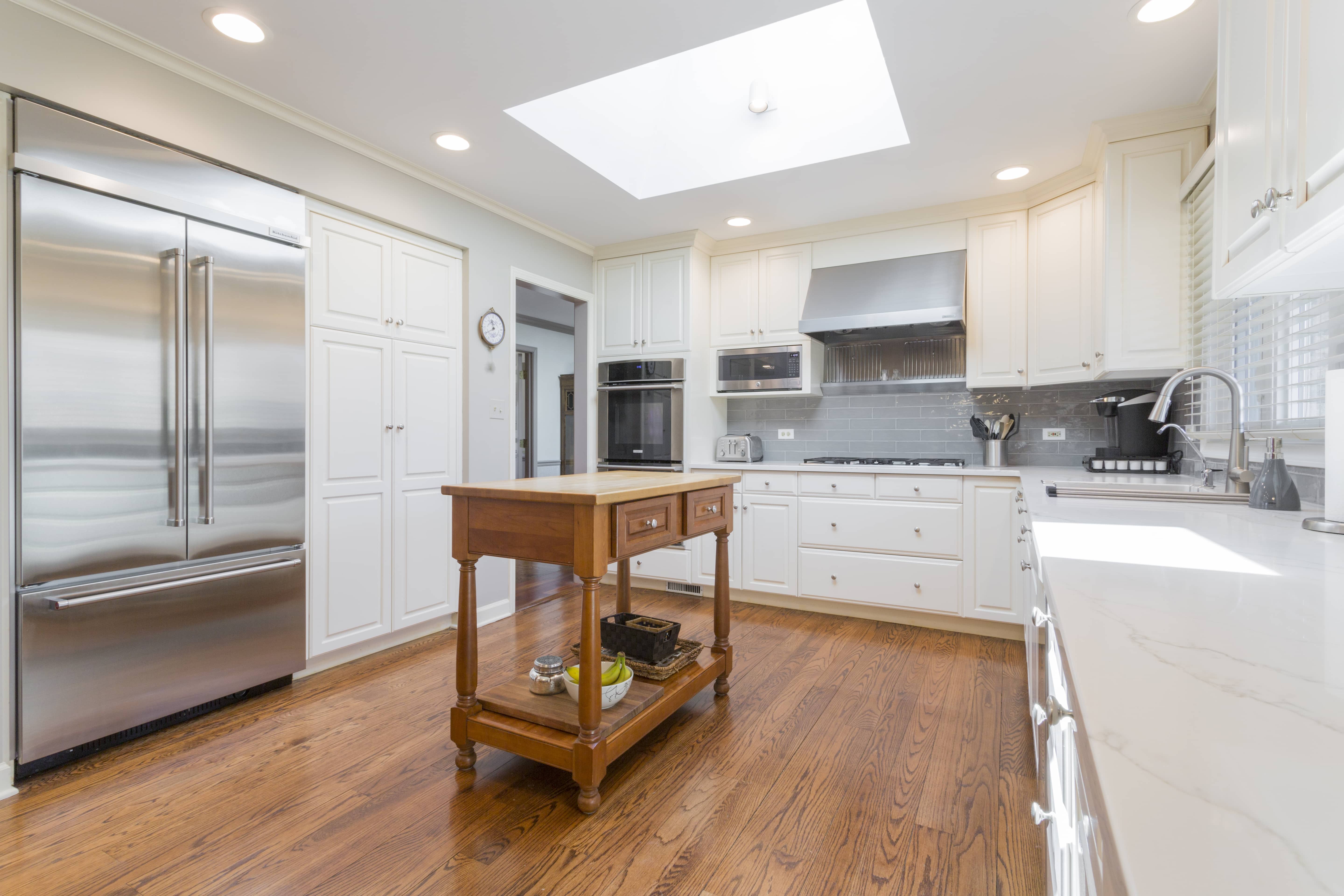 Cream and brown kitchen with wood floors and console island. 