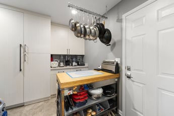 Butler's pantry with butcher block countertop, pot rack, and floor to ceiling cabinets 