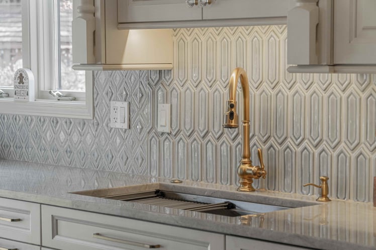 Kitchen sink with gold faucet and grey tile 