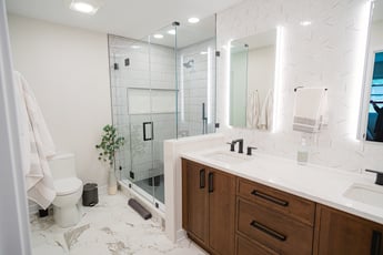 Bathroom with backlit mirrors, a walk-in shower, and brown vanity 