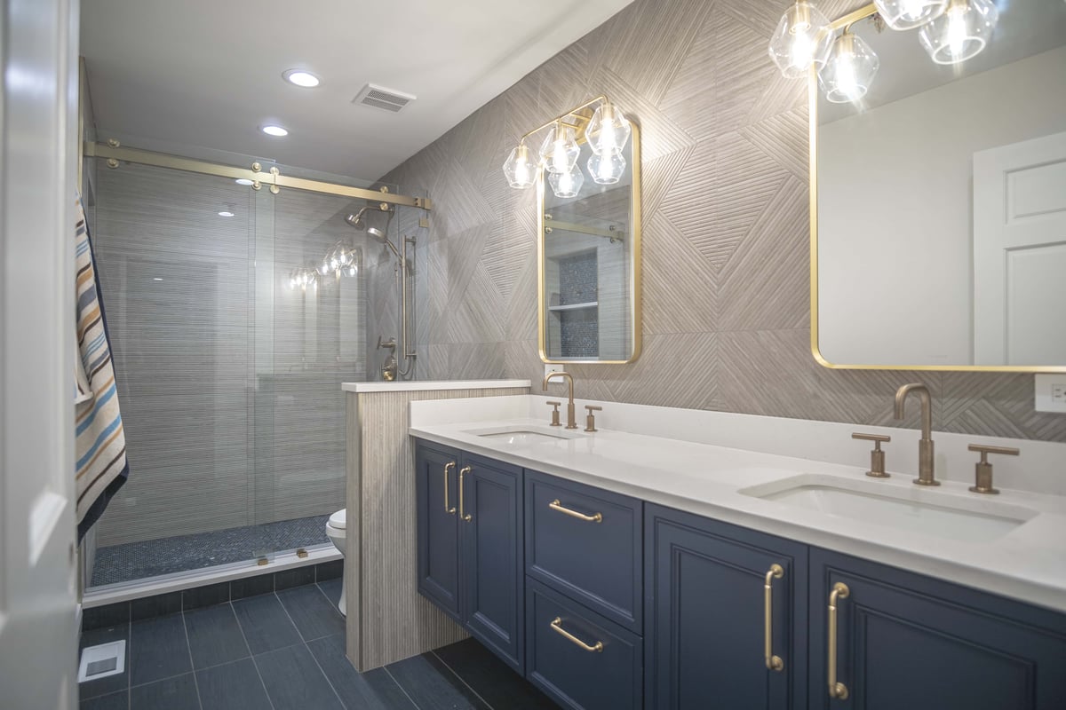 bathroom with blue cabinets gold hardware double sinks and walk-in shower 
