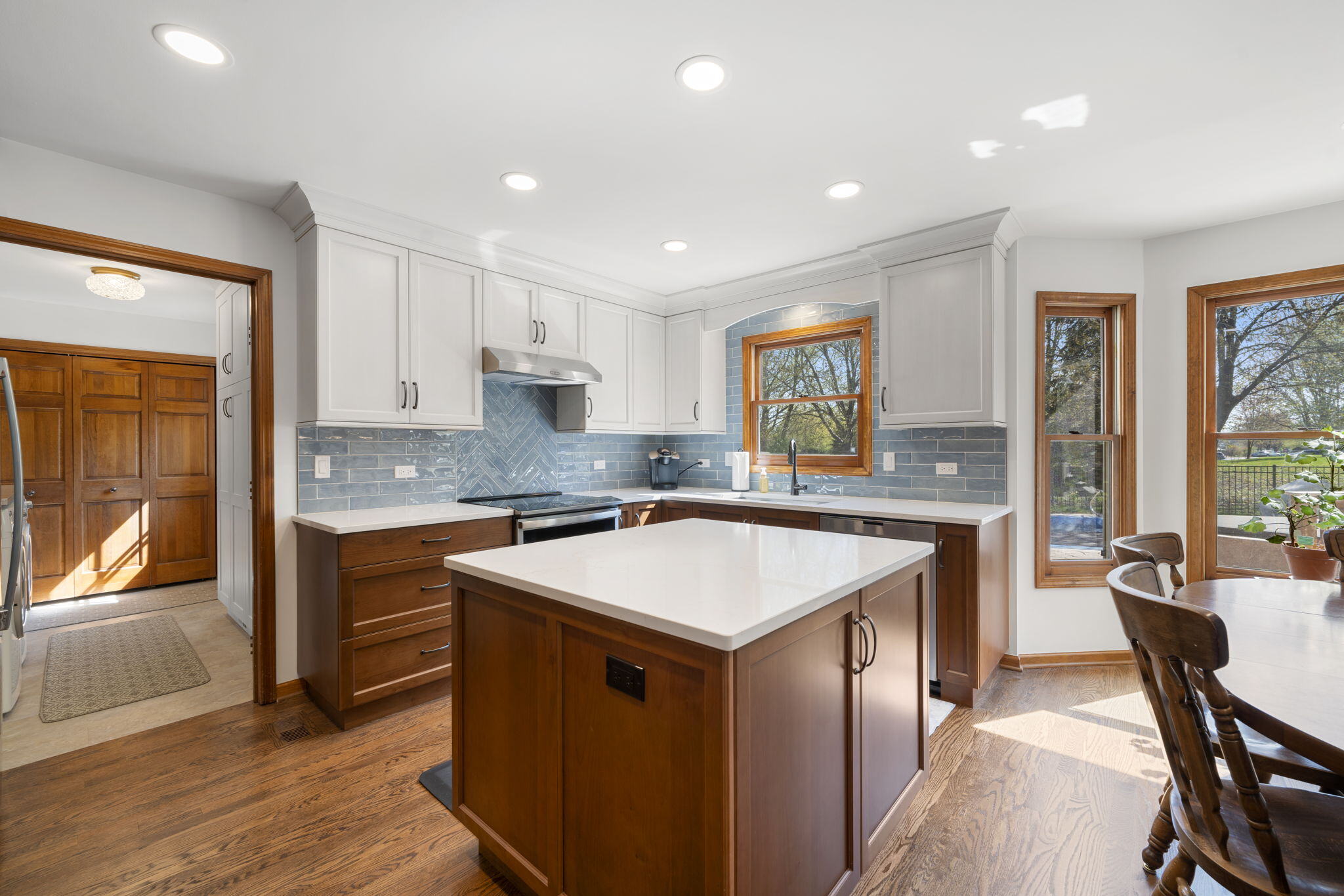 Kitchen with square island white countertops and cinnamon cabinets 