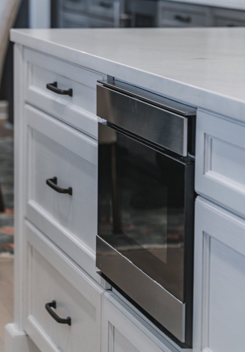 white cabinets with black hardware and built-in stainless steel microwave