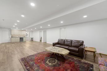 basement with light beige LVT flooring, recessed can lighting, a leather couch, and a wet bar 